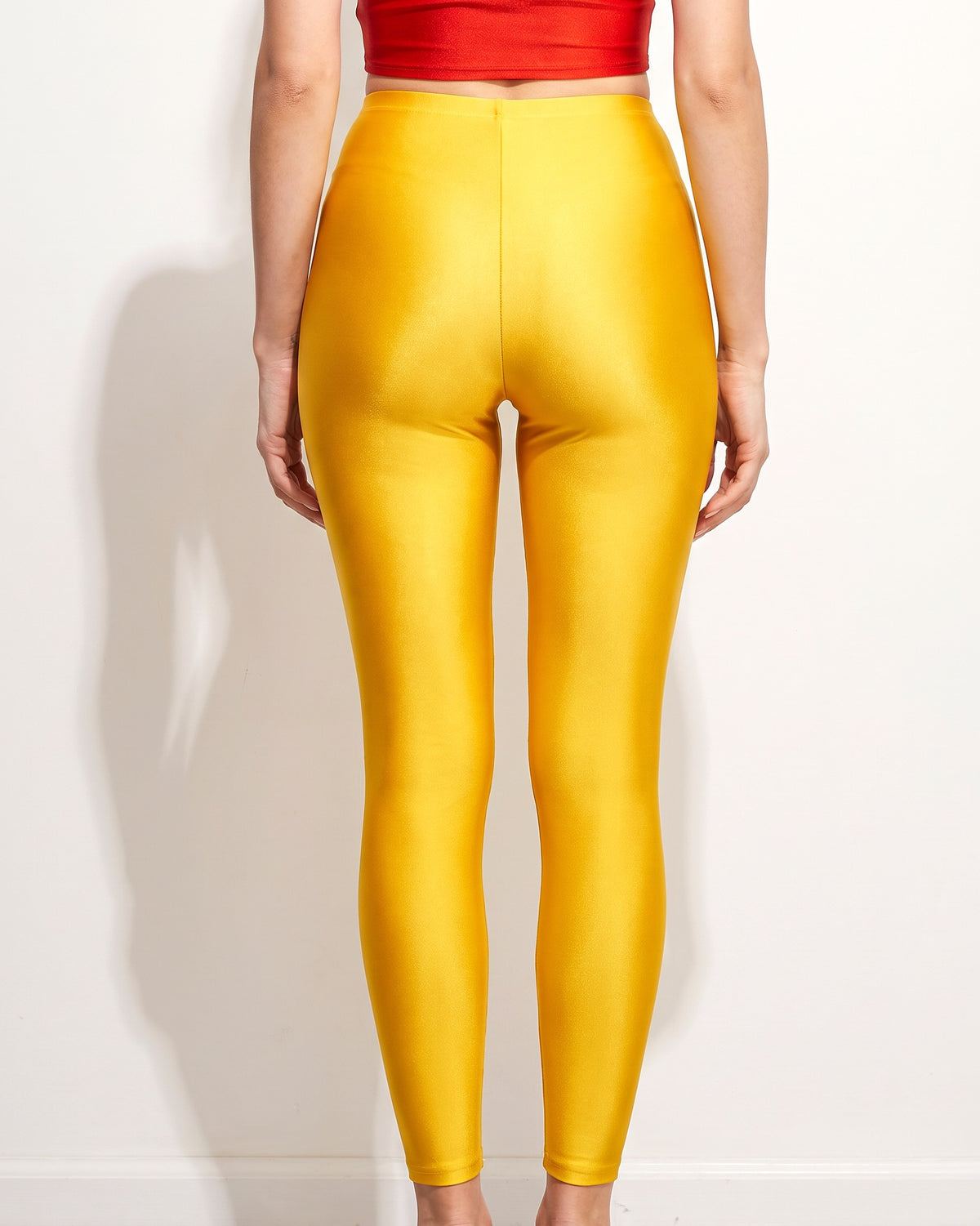 Yellow gold shiny tricot leggings, back view on model
