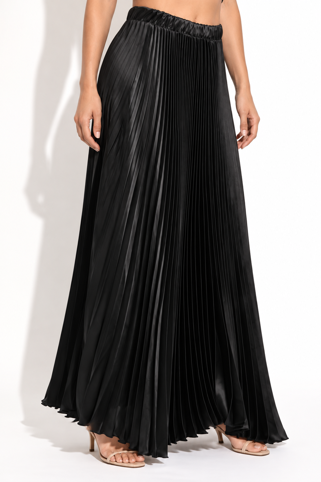 Black pleated satin maxi skirt, front angled view showing satin sheen and flowing maxi length