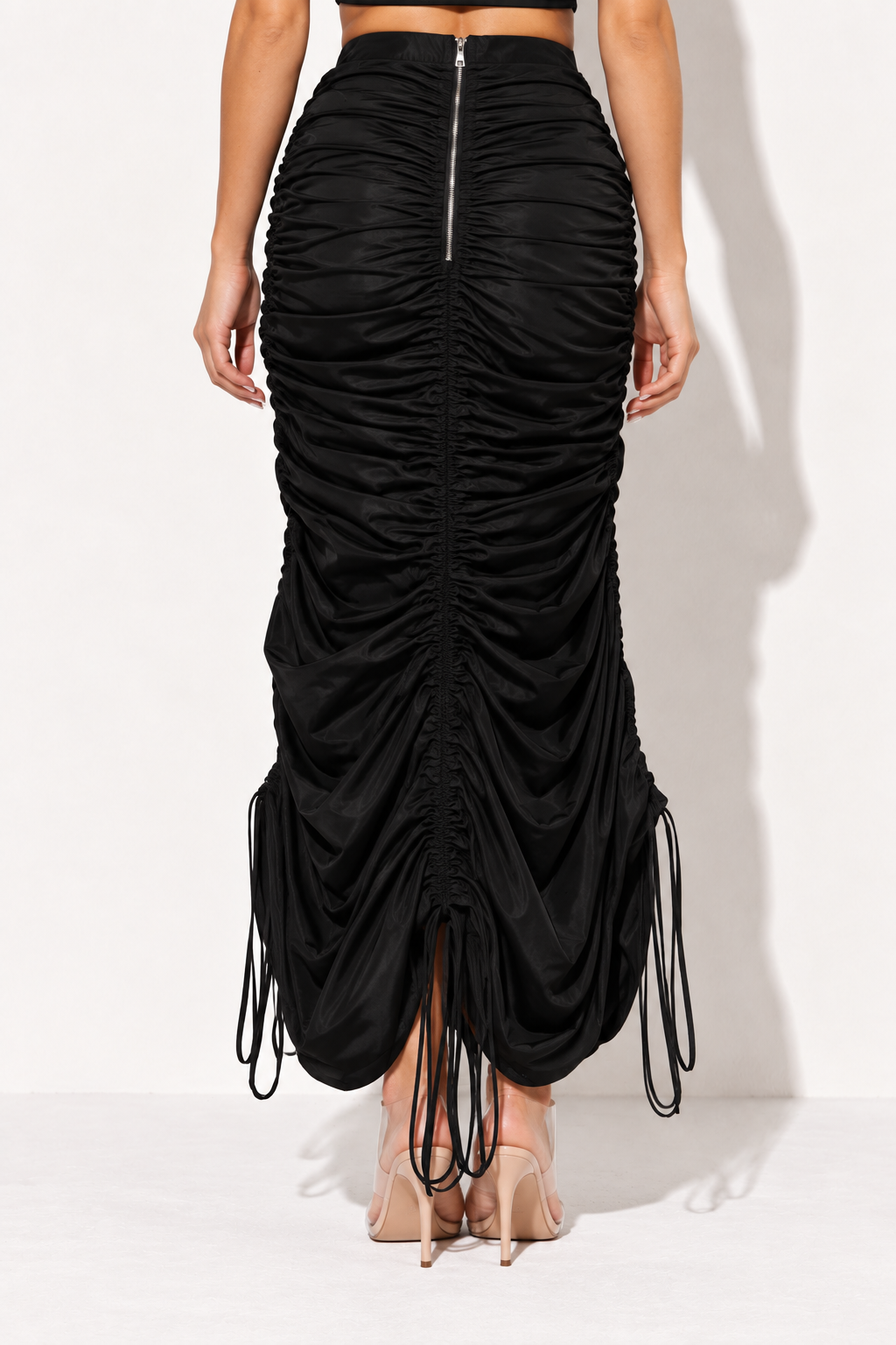 Black ruched drawstring maxi skirt, rear view showing silver zipper and gathered center seam
