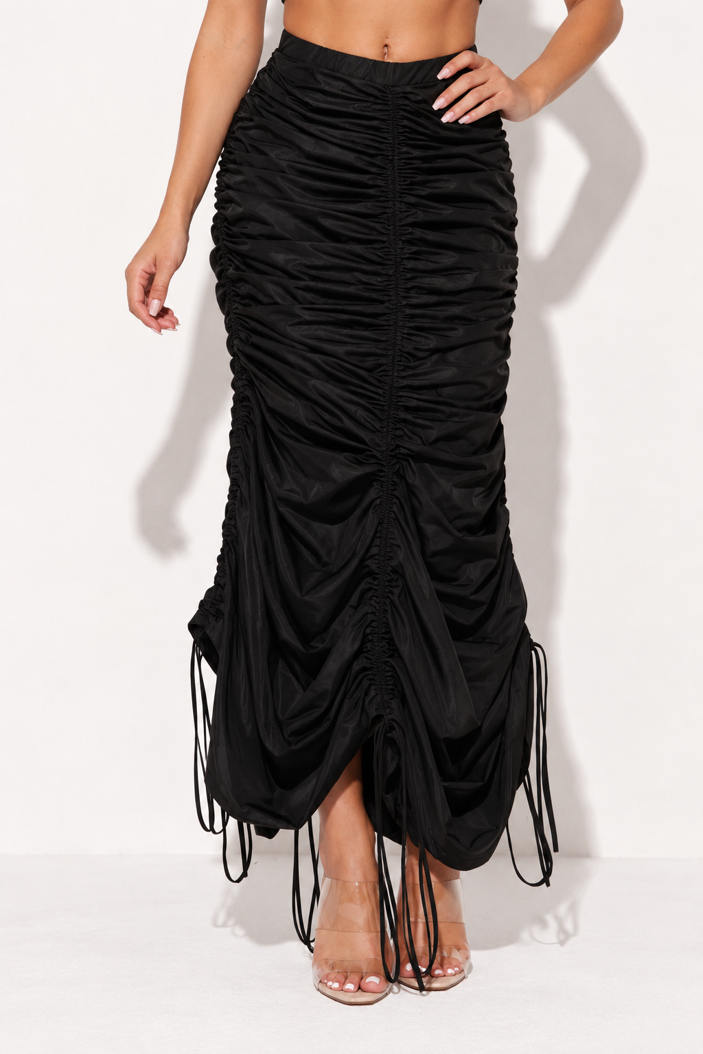 Muvin women's black ruched drawstring maxi skirt, front view showing gathered fabric and scalloped hem