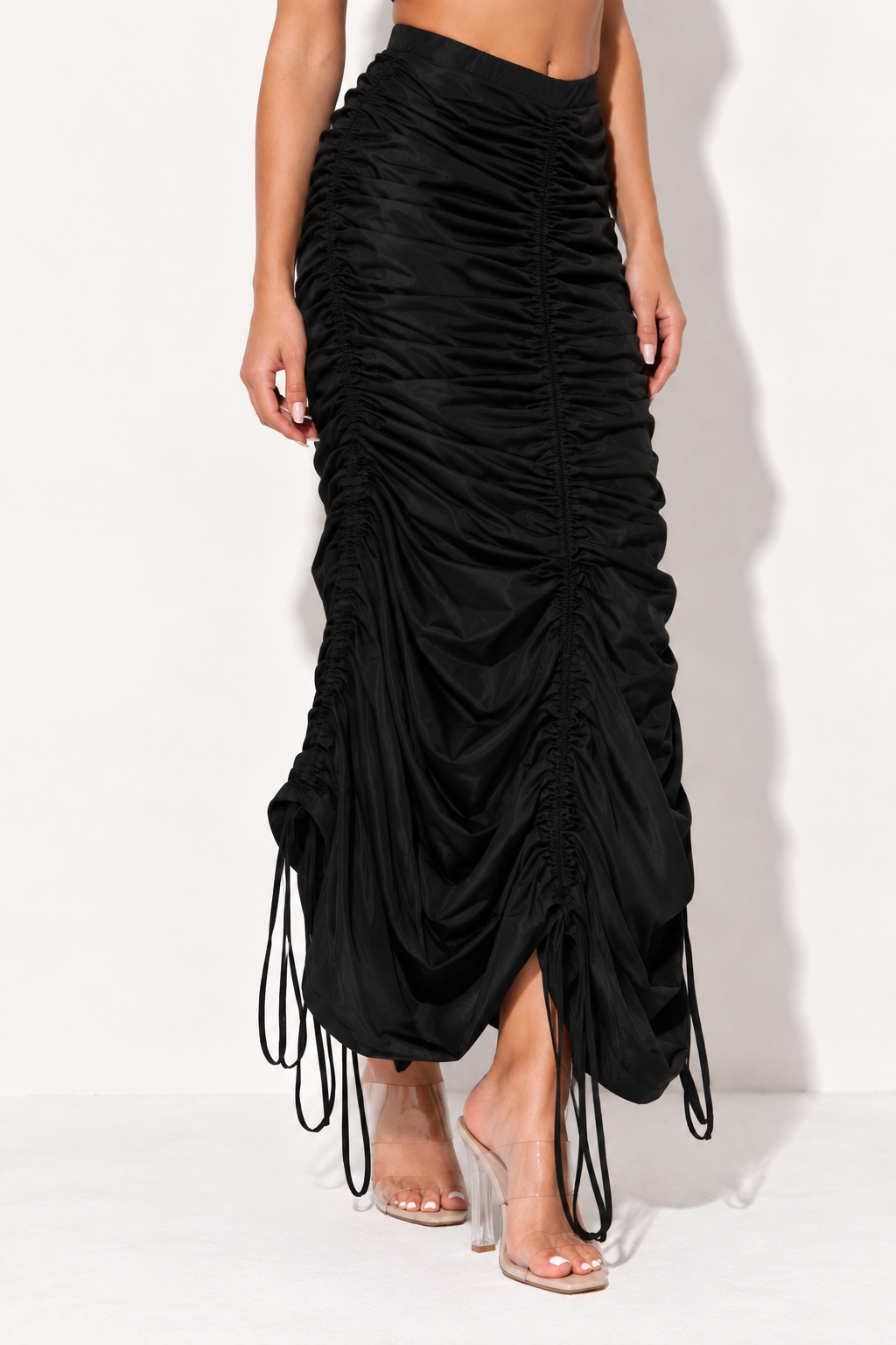 Black ruched drawstring maxi skirt, angled front view showing side ruching and hanging drawstrings