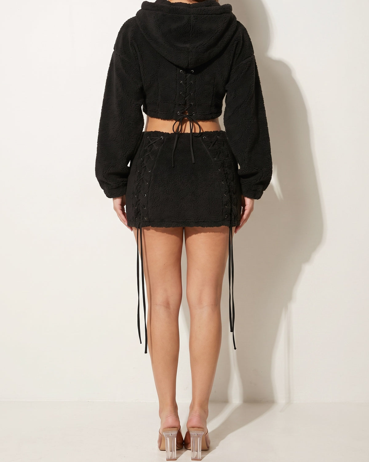 Black sherpa lace up detailed mini skirt and hoodie set, back view on model