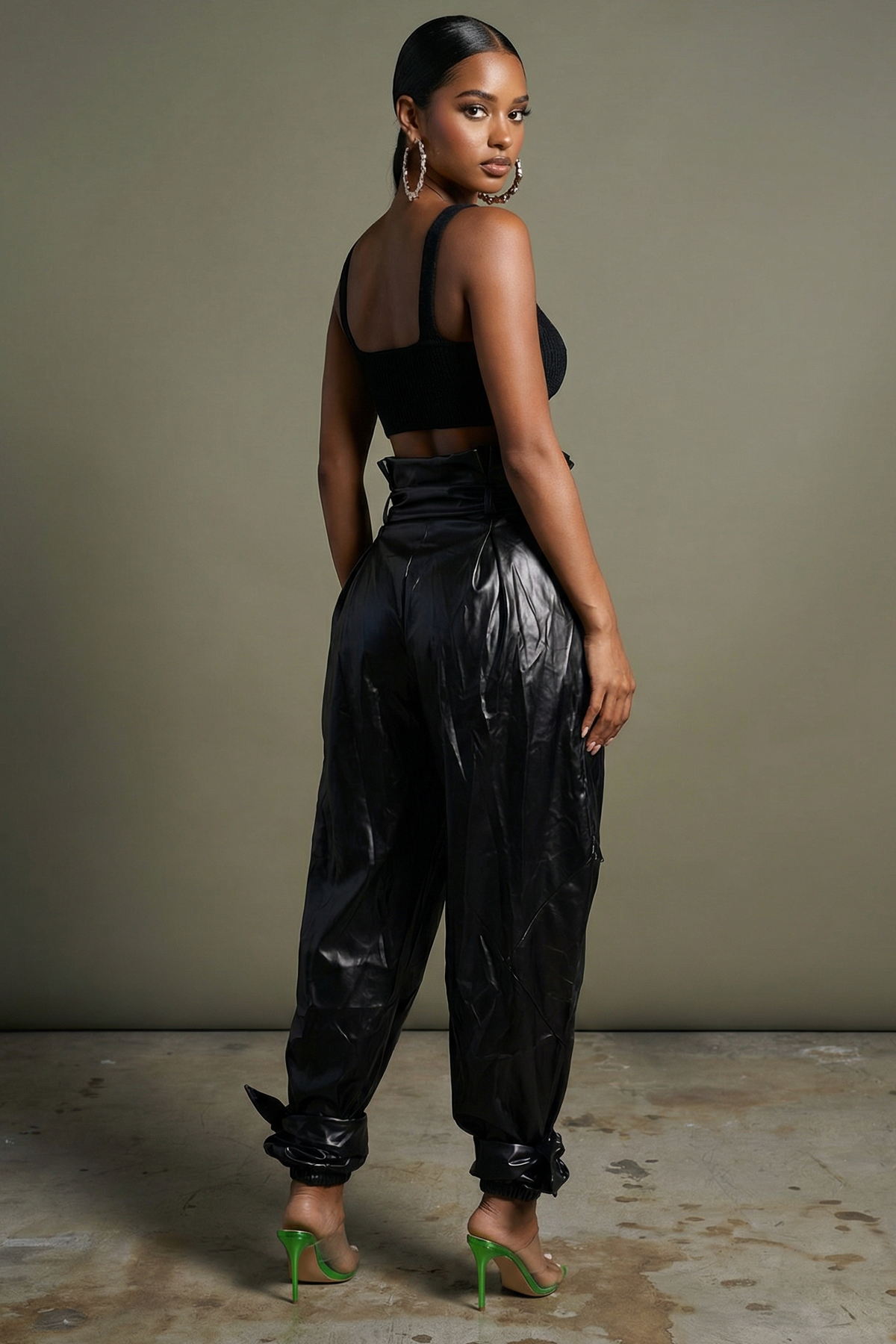 Black metallic PU leather jogger pants showing tapered silhouette