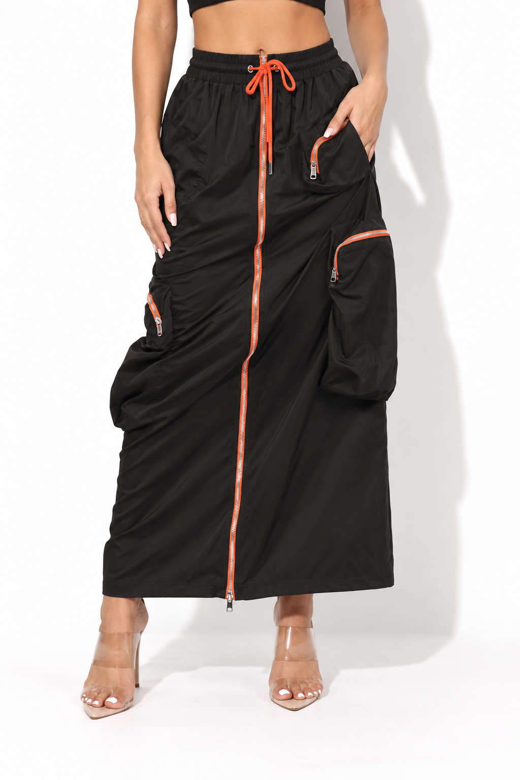 Black drawstring cargo maxi skirt with orange zippers, front view showing orange center zipper and drawstring waist