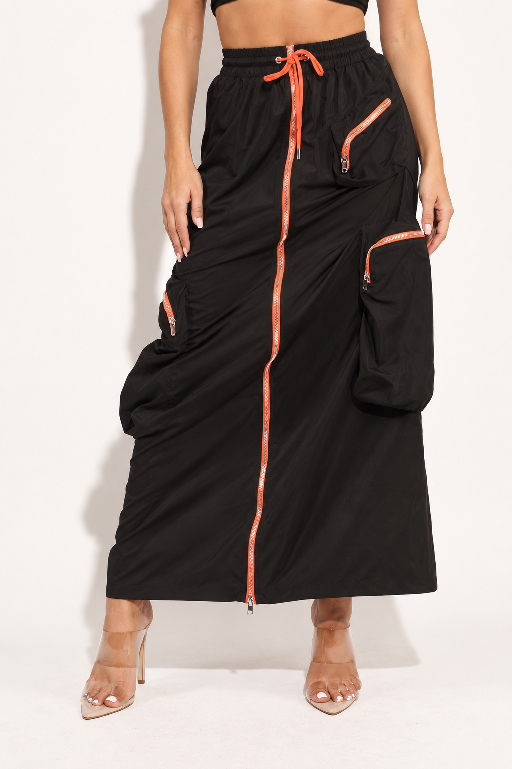 Black drawstring cargo maxi skirt with orange zippers, front angled view showing zippered hip and oversized cargo pockets