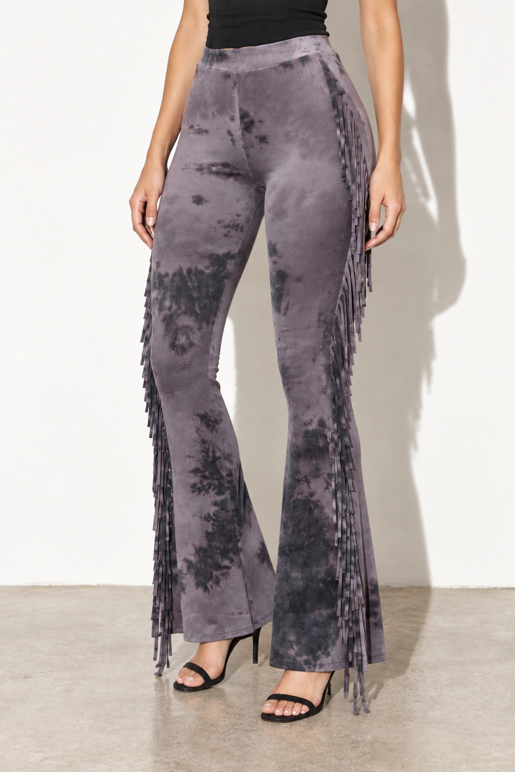 Grey combo tie dye fringe flare pants, angled front view showing long outer seam fringe and flared hems