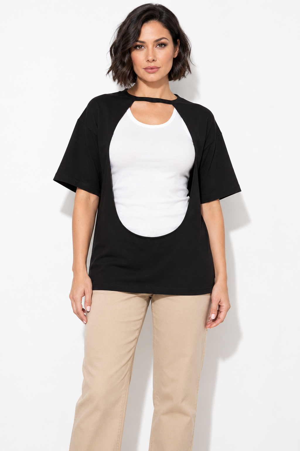 Black front cutout oversized top styled over a white tank with beige trousers