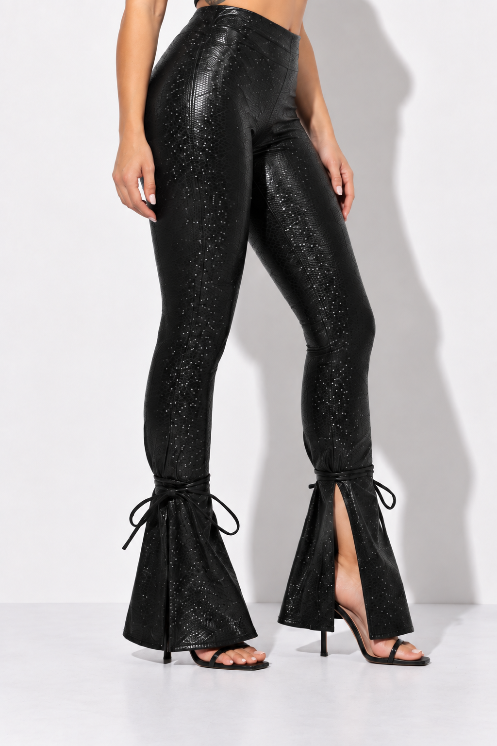 Black textured PU split hem pants, angled front view showing outer hem splits and reptile texture