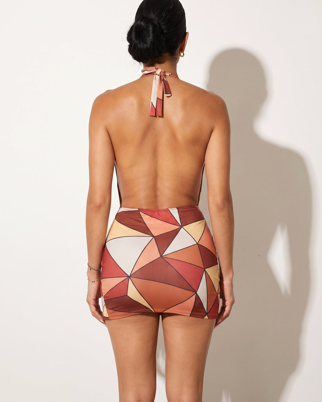 Brown multicolor triangle color block printed halter mini dress, back view on model