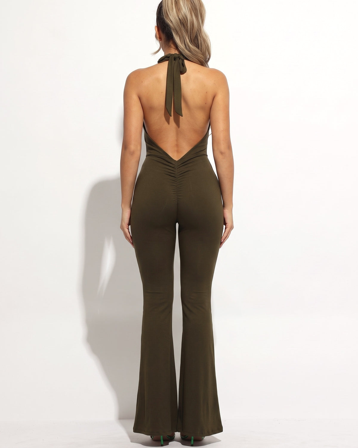 Olive halter deep V neck flare jumpsuit, back view on model