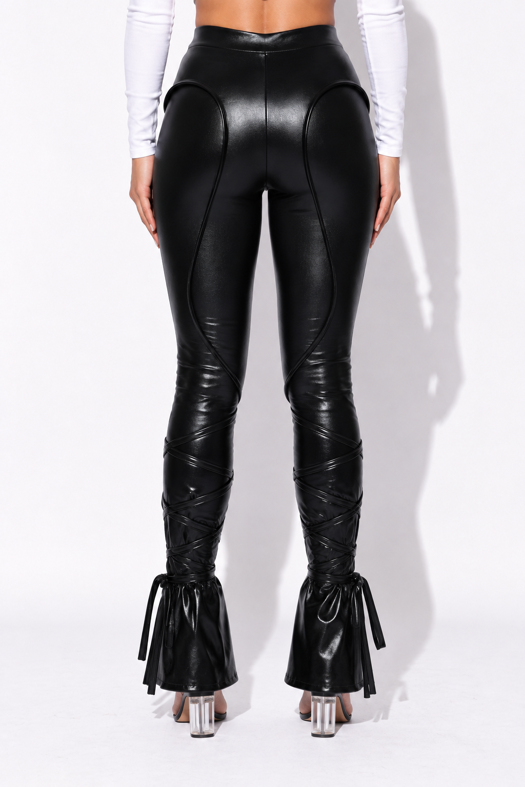 Black metallic pants with curved panel seams and calf ties, back view showing curved hip seams and tied lower legs