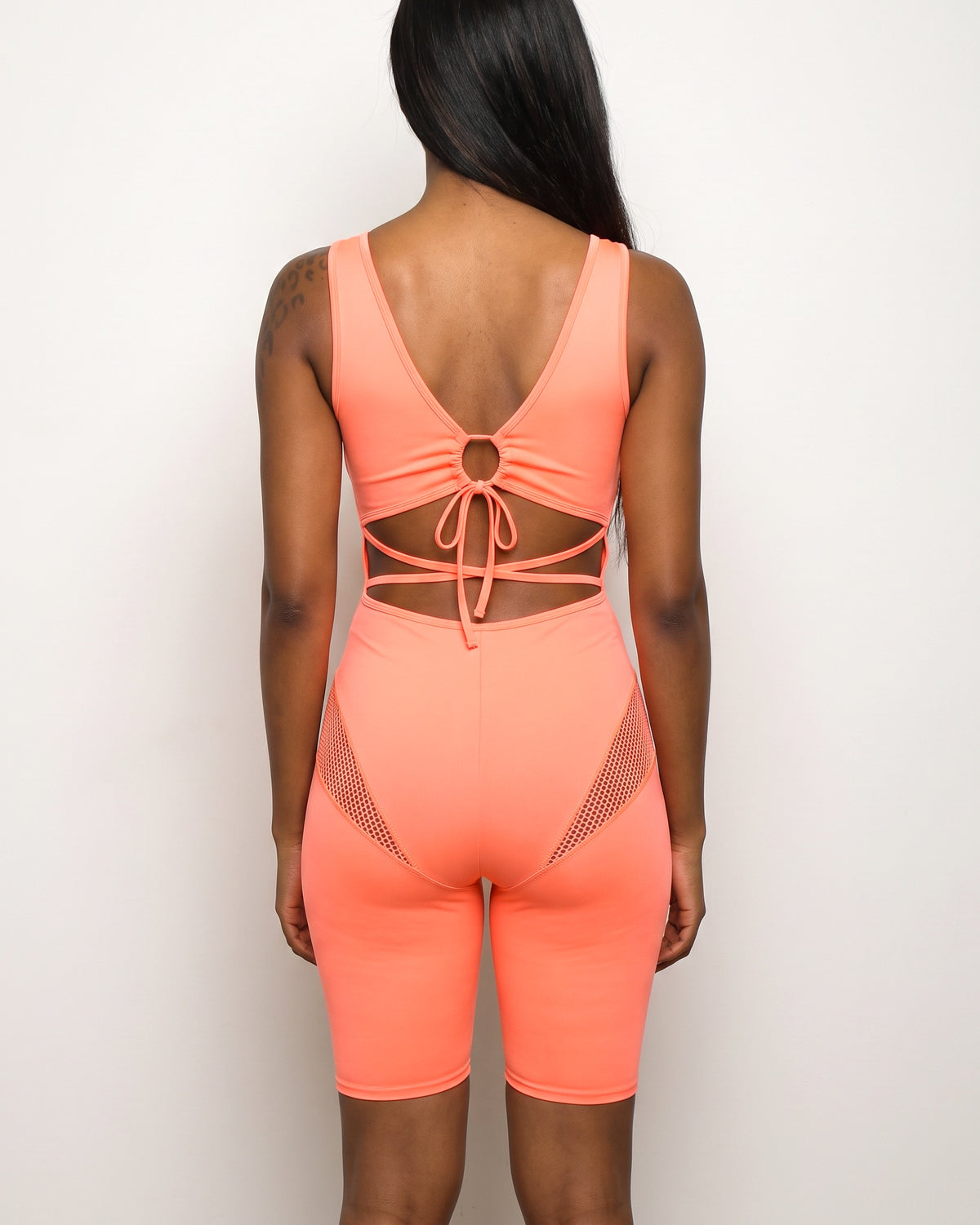 Coral fishnet detailed romper, back view on model